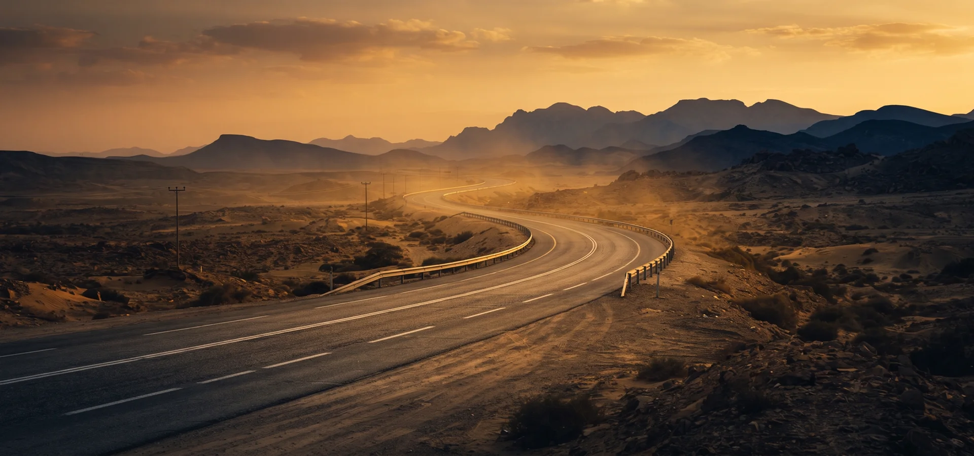 Desert highway curving toward distant hills at sunset