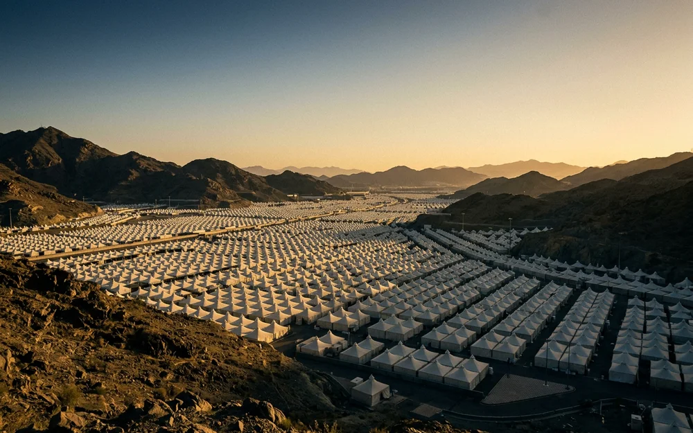 Rows of white tents at Mina seen from a hillside in early morning light