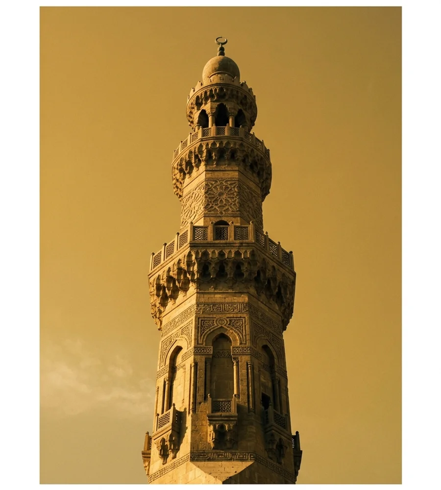 Minaret with carved geometric stonework against a golden sky