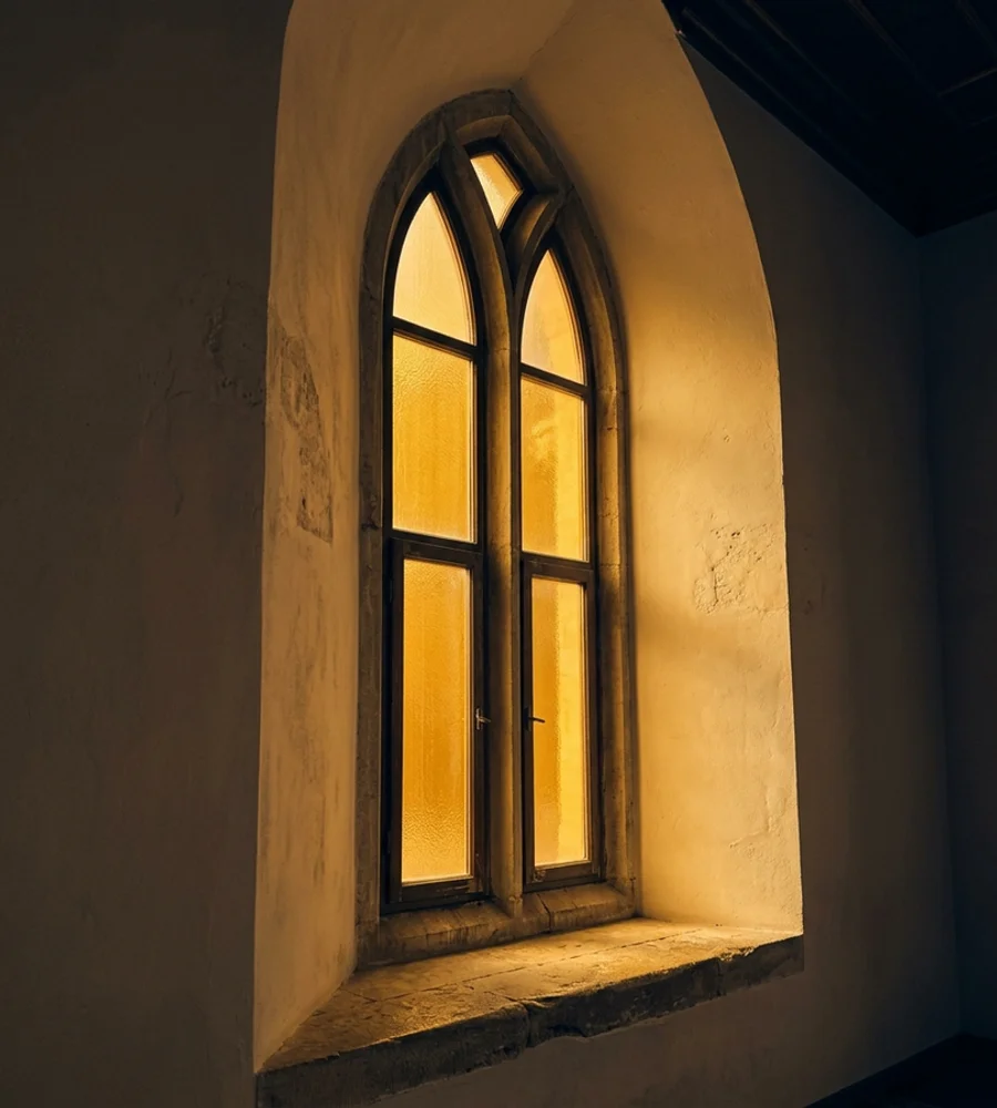 Tall arched window with amber glass casting warm light